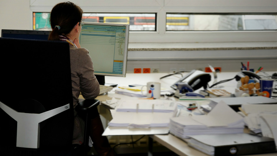 mulher trabalha em escritório com computador e papéis