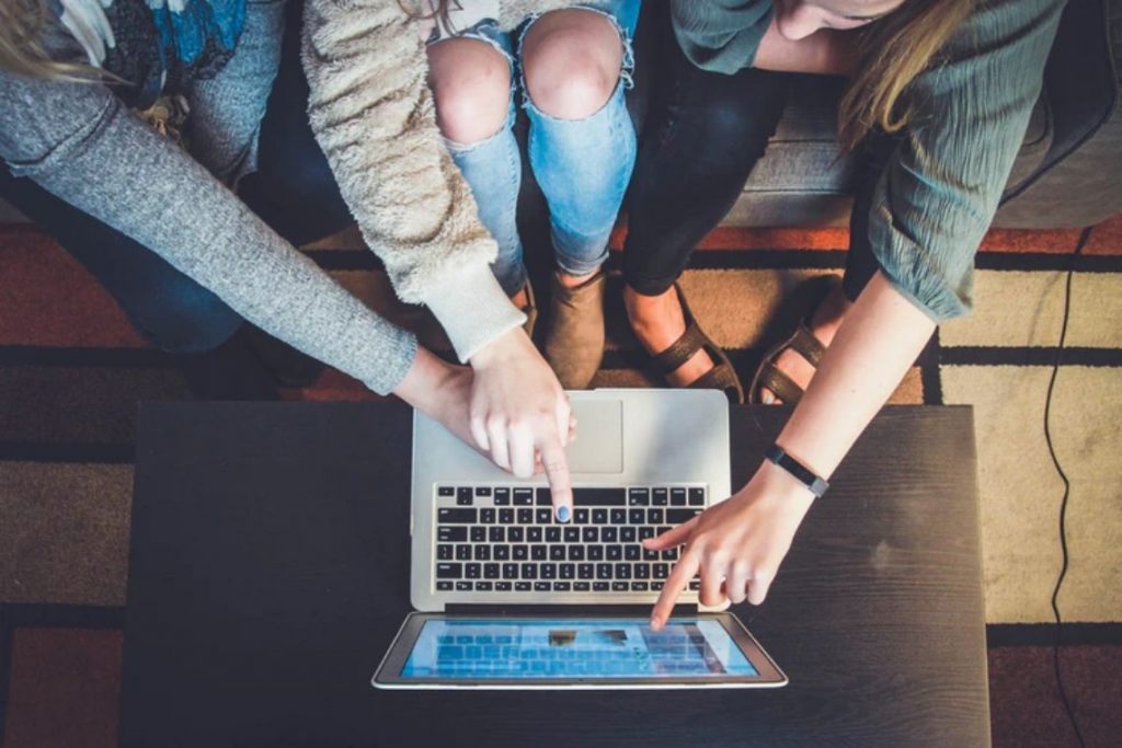 grupo de jovens apontando para tela do notebook